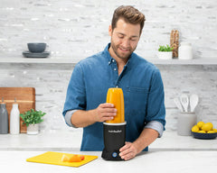 man making an orange smoothie in the kitchen