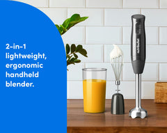 A nutribullet Lite handheld blender displayed on a kitchen counter beside a whisk, blending cup, and plant, emphasizing its compact, 2-in-1 design.