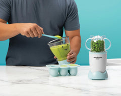 NutriBullet Baby with batchbowl and easy pop freezer tray on blue background.