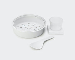 Kitchen utensil set including a steamer with holes, a spoon and a measuring cup
