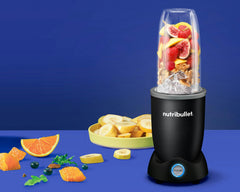 matte black nutribullet pro plus filled and fruit on the counter on a purple background