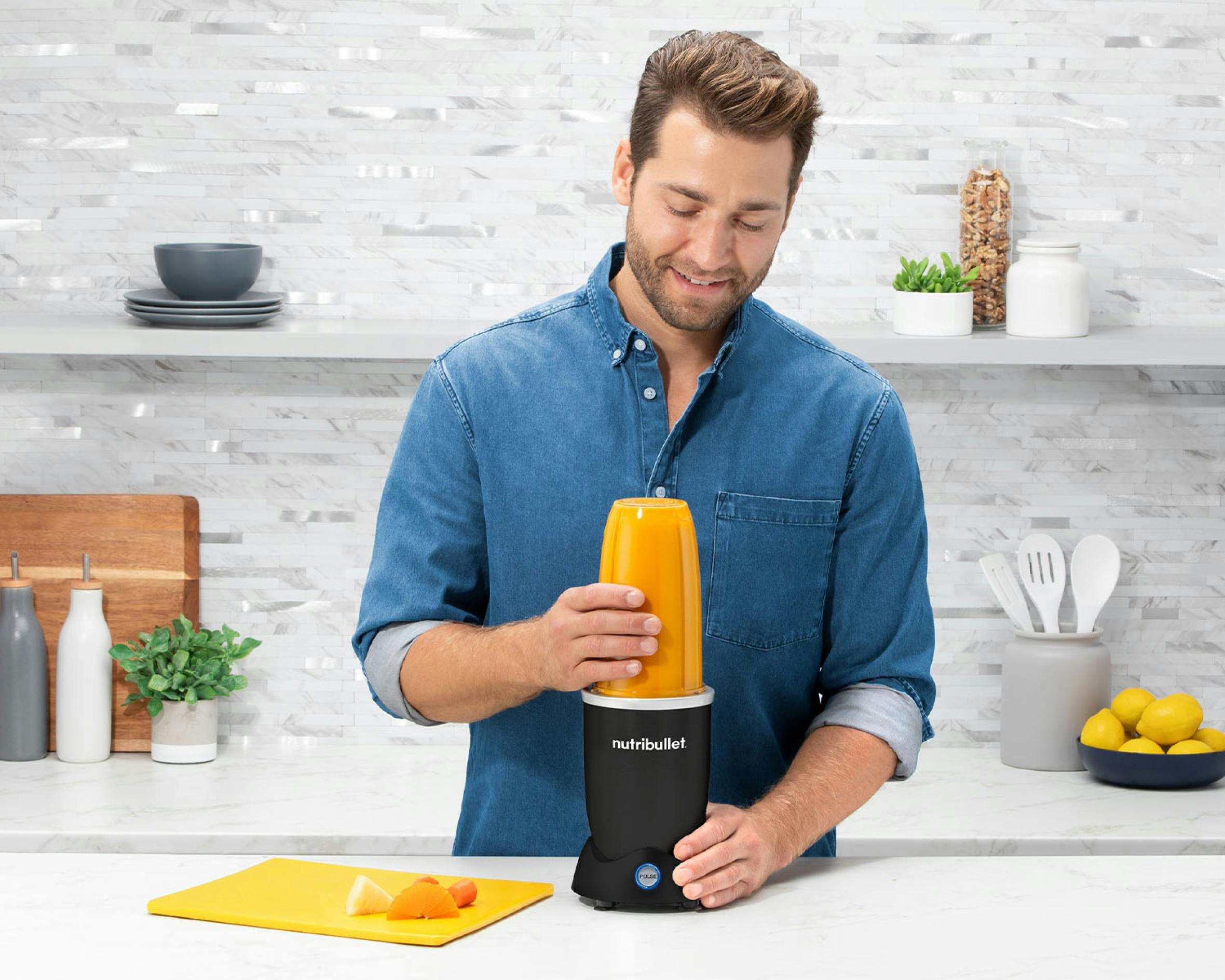 man making an orange smoothie in the kitchen