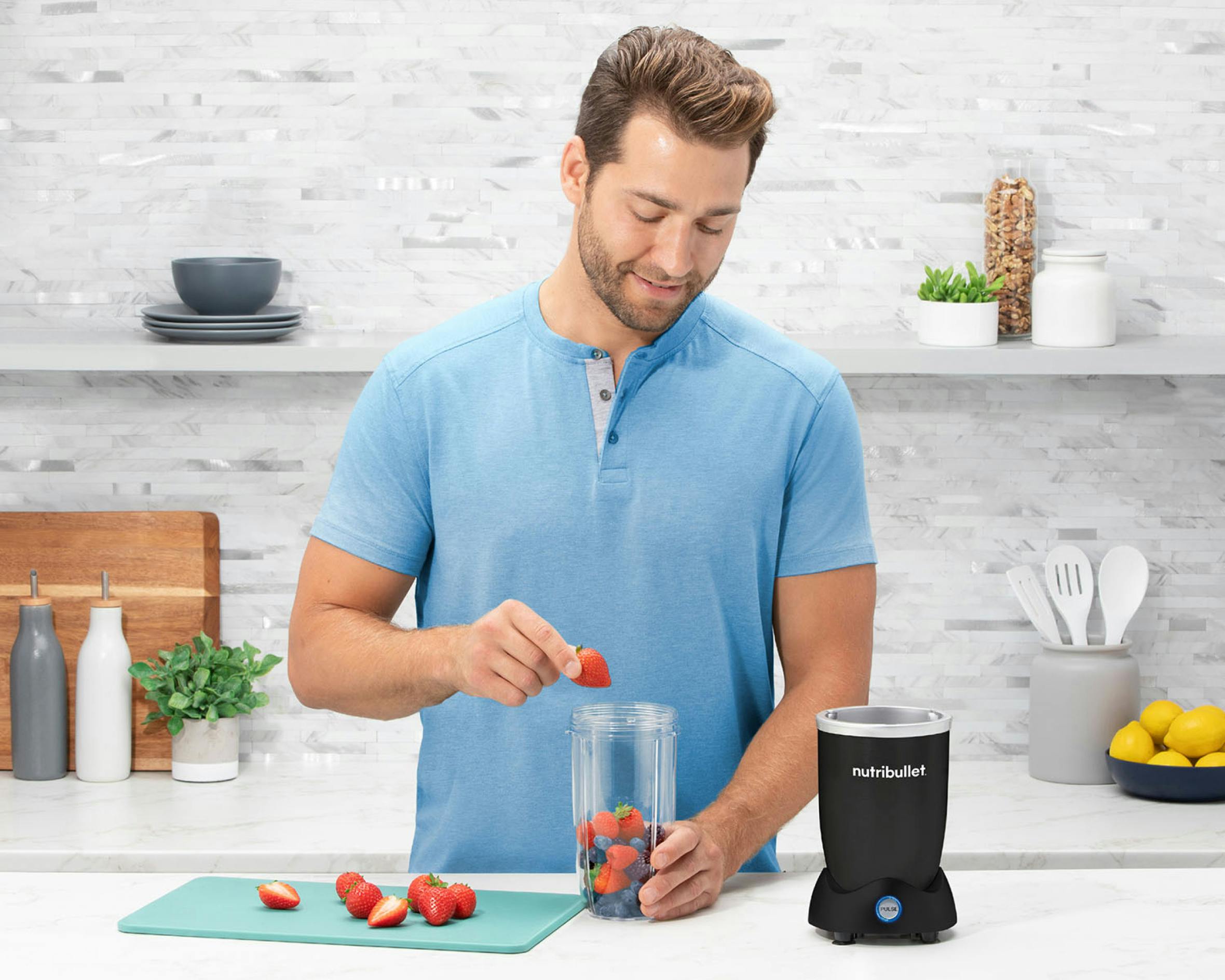 man adding berries to the matte black nutribullet pro plus in the kitchen