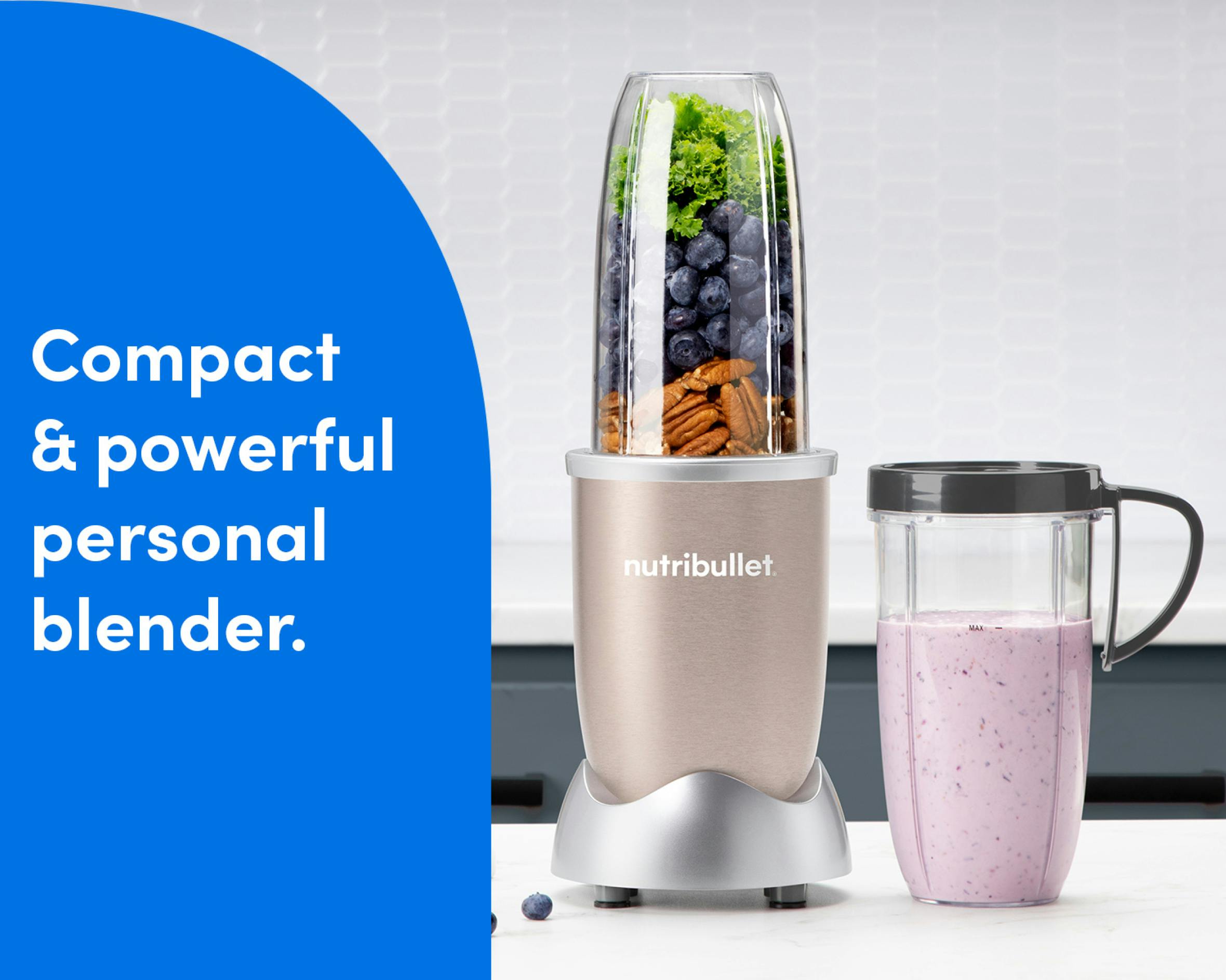 The nutribullet Pro rests on a white countertop. The Tall Cup is attached to the Power Base and filled with a variety of unblended fruits and vegetables. A Tall Cup with the Handled Lip Ring attached rests to the right of the blender, filled with a light pink smoothie.