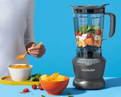 NutriBullet Blender with soup ingredients on blue background.