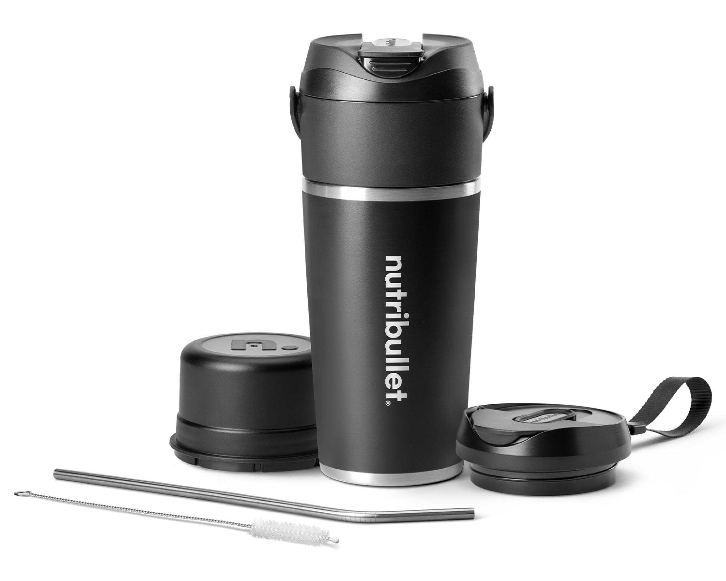 nutribullet Flip full configuration. The black insulated tumbler is shown with the sip-through blade attached at the top. The blade cover rests to the left of the tumbler, and the to-go lid is situated to the right. A metal straw and straw-cleaning brush rest in front of the tumbler at an angle.
