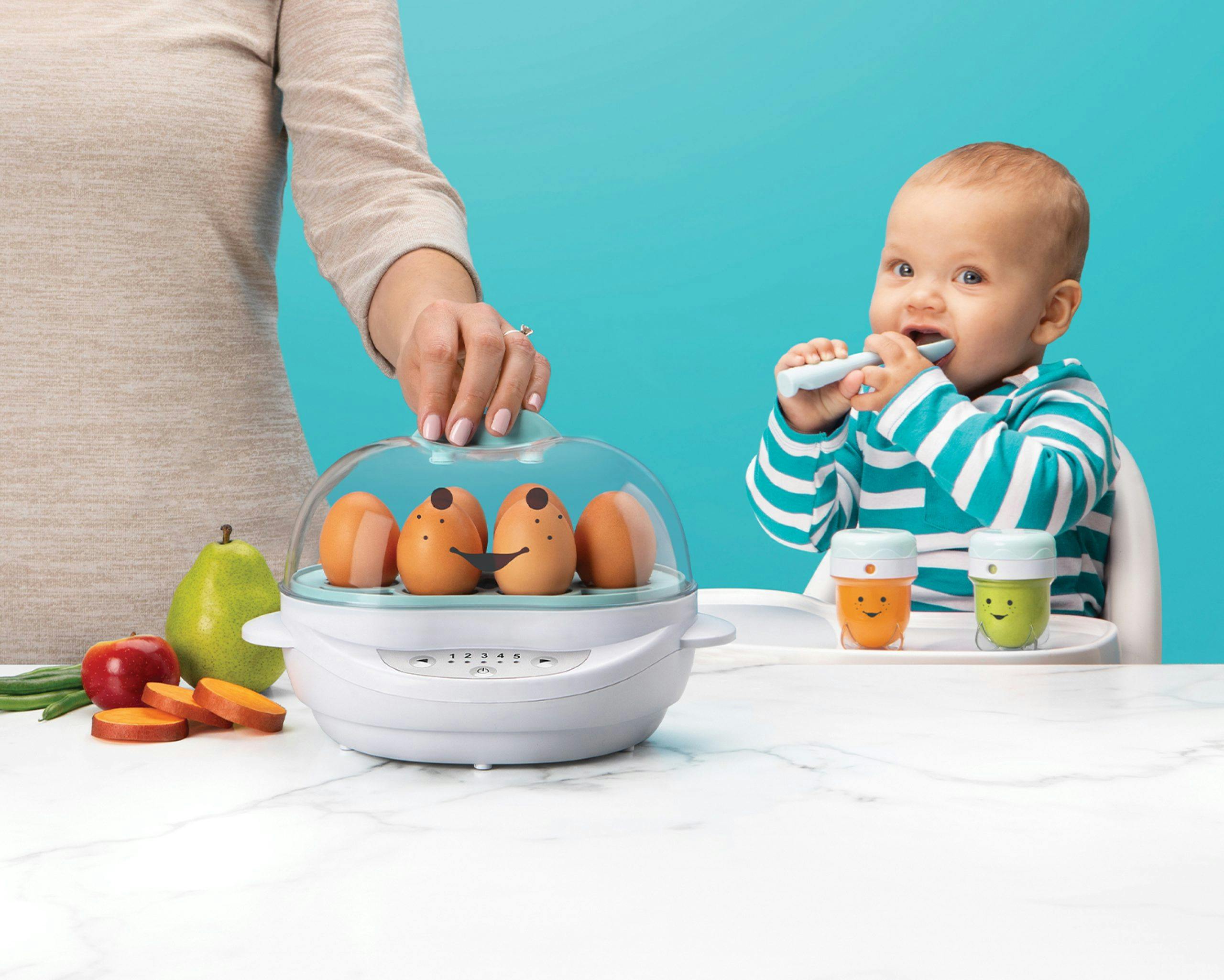 NutriBullet Baby Steamer with eggs next to fruits and veggies with mother's hand and baby eating in background.