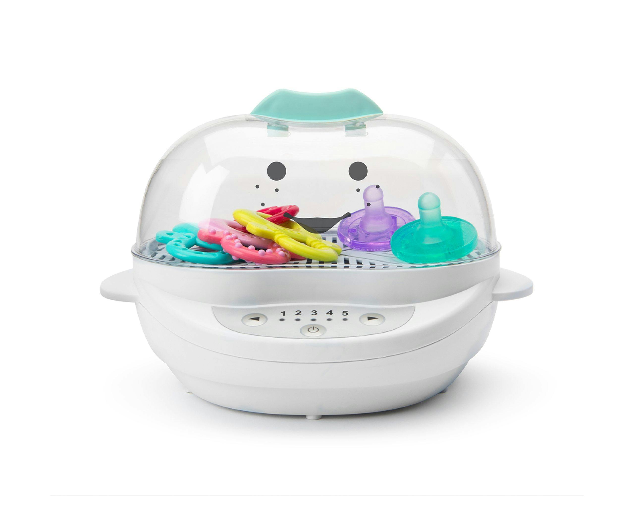 White NutriBullet Baby Steamer filled with toys and pacifiers with teal accents with smiley face
